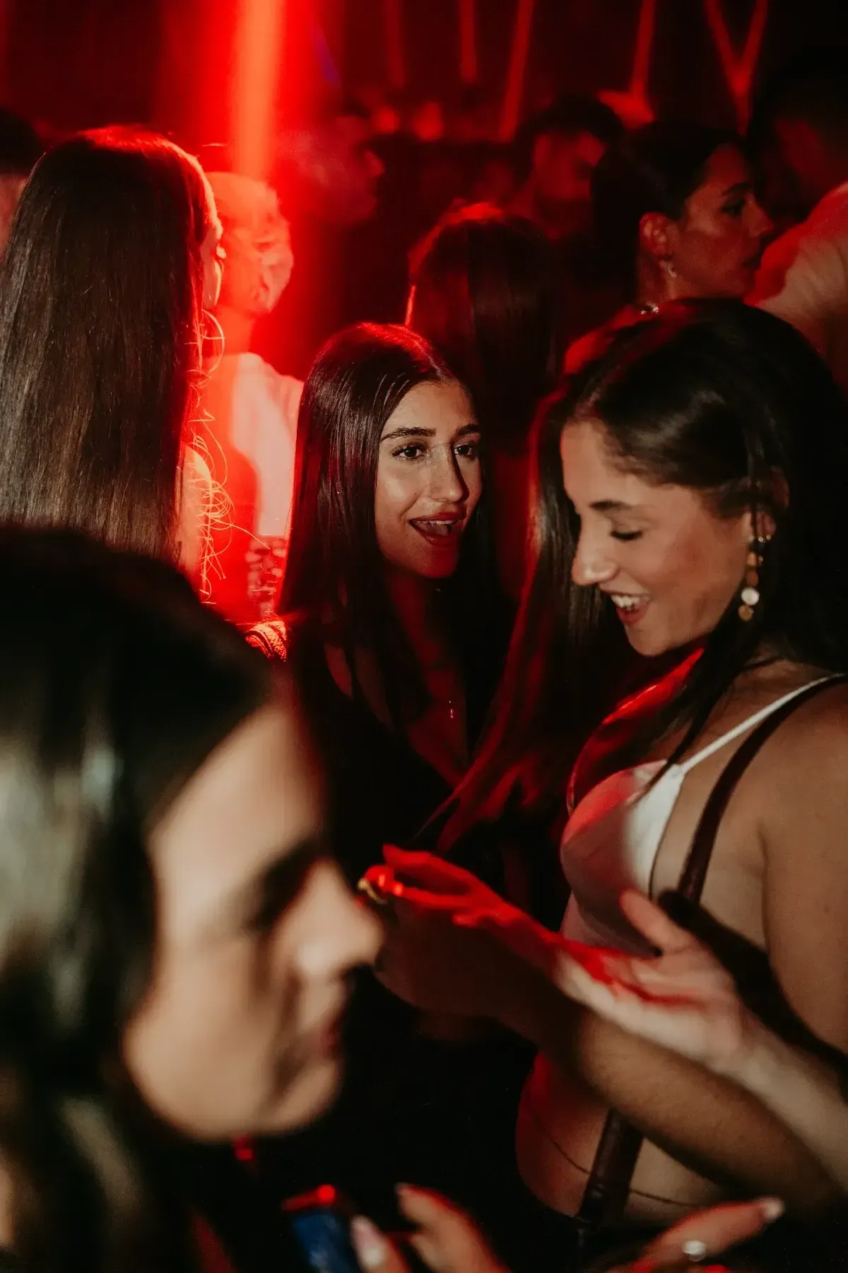 Grupo de amigas celebrando en un reservado con luz roja